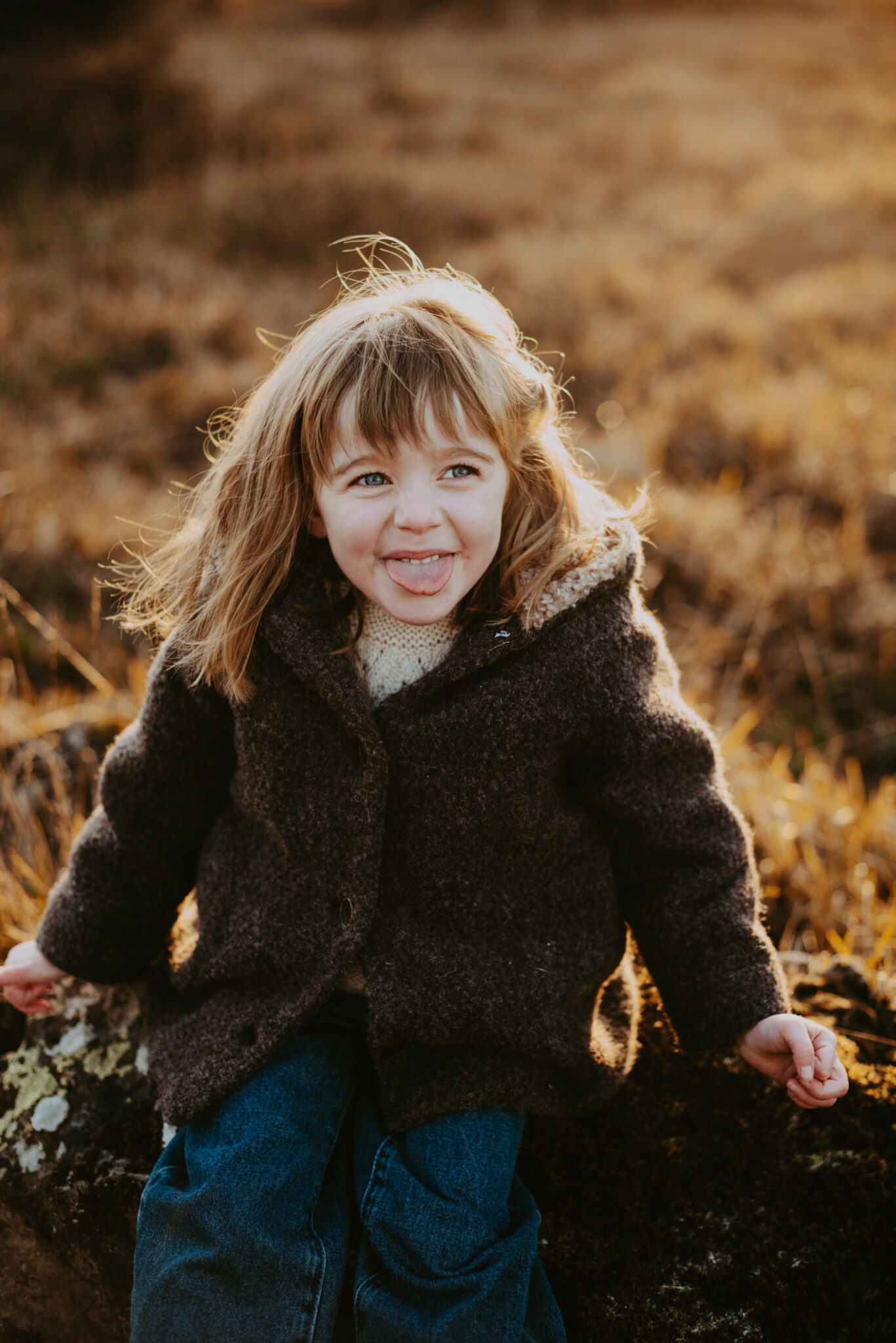 portrait d'une petite fille assise dans la nature et qui tire la langue