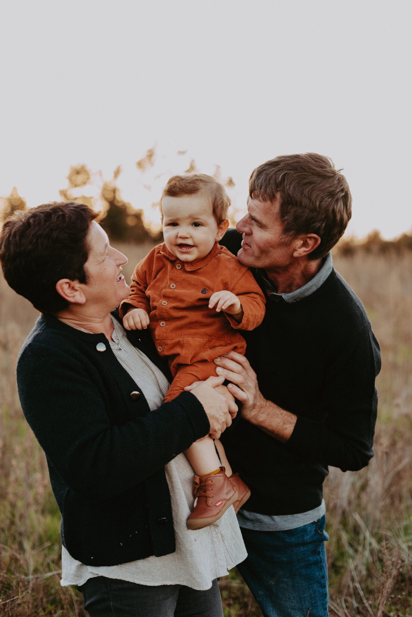 photo d'un jeune enfant avec ses grand parents enlacer dans un champ