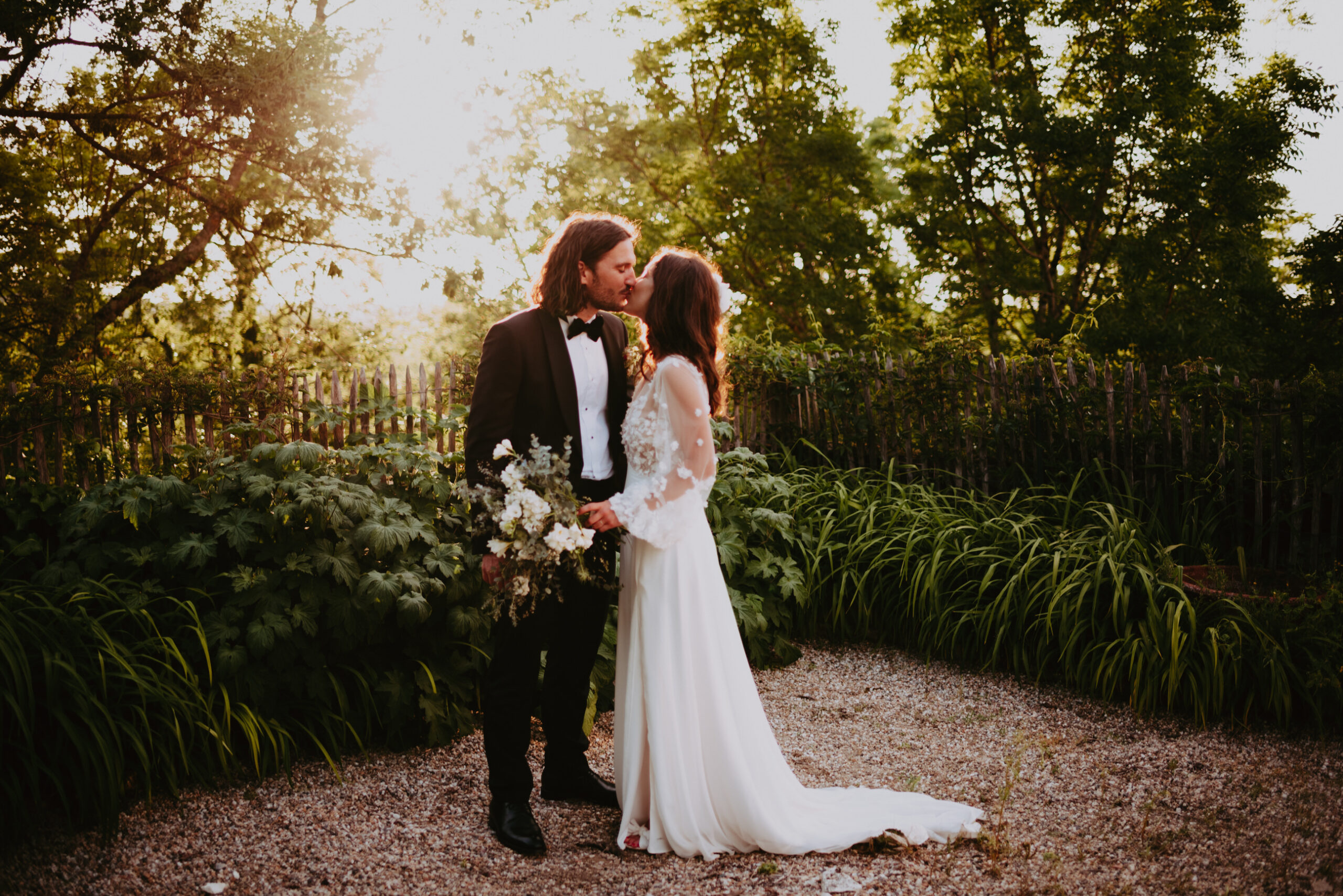 un couple de jeune mariés s'embrasse au coucher de soleil dans la nature de la Dordogne le soir de leur mariage