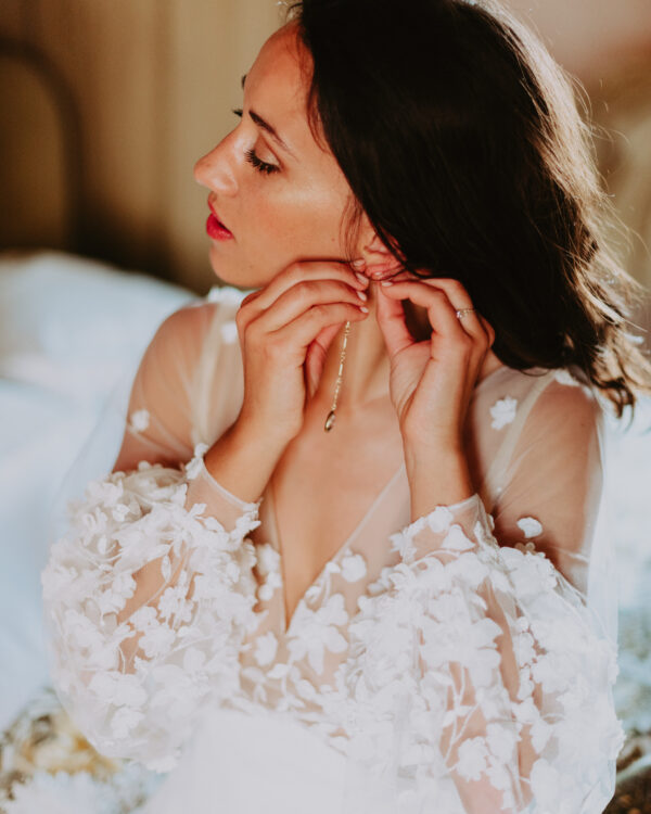 détail d'une mariée qui enfile ses boucles d'oreilles