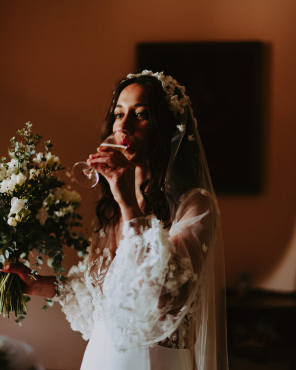 une mariée boit du champagne dans sa magnifique robe de mariage
