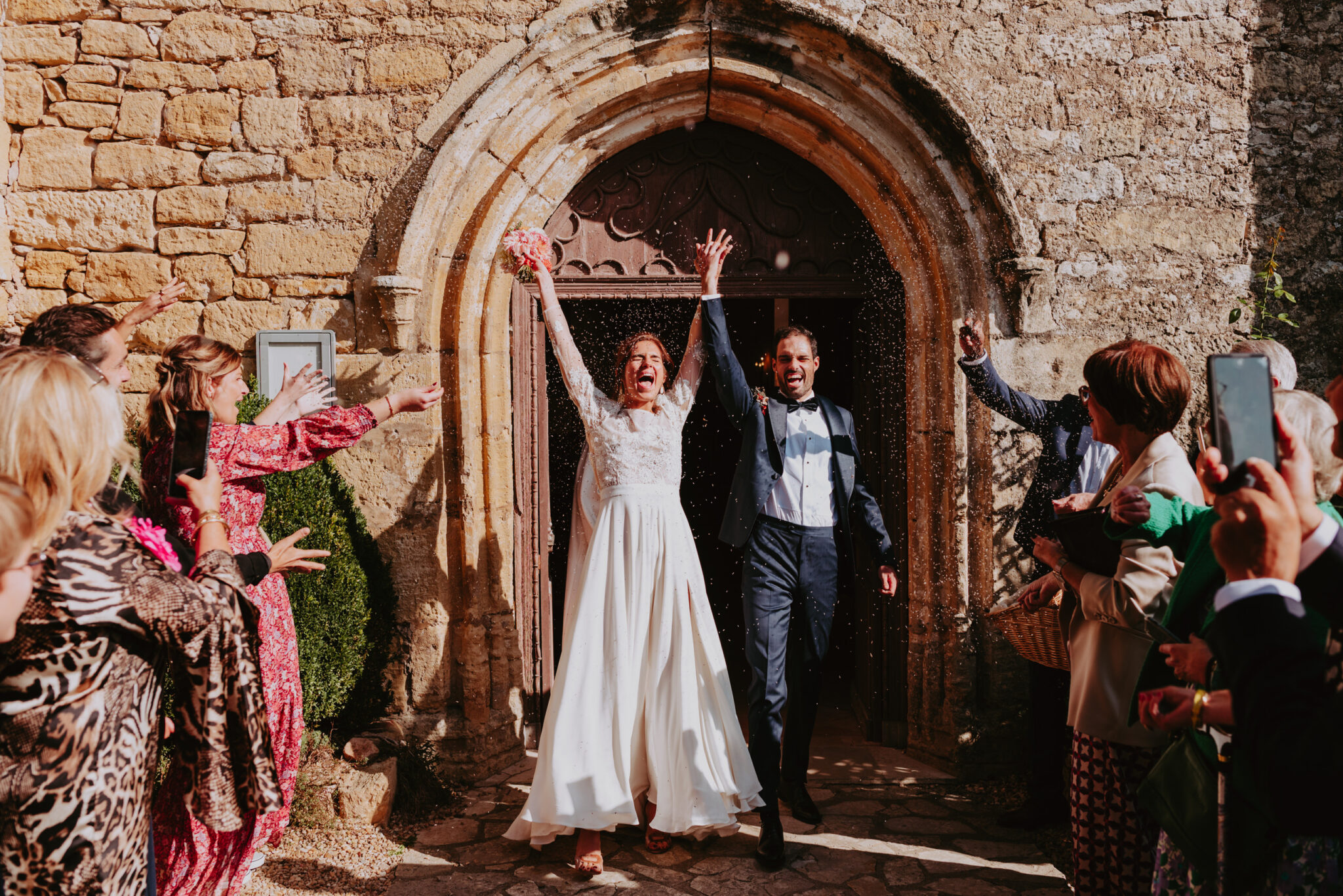 couple de marié qui sortent de l'église main dans la main sous une pluie de lavande